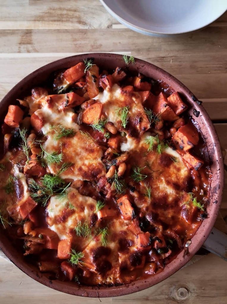 A pan of baked vegetables and cheese topped with dill