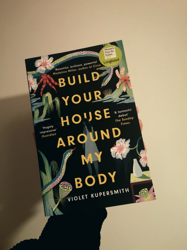 A copy of Build Your House Around My Body by Violet Kupersmith is black with plants and snakes on the cover