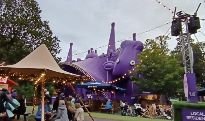 A festival garden strewn with lights and a giant upside down cow-shaped tent